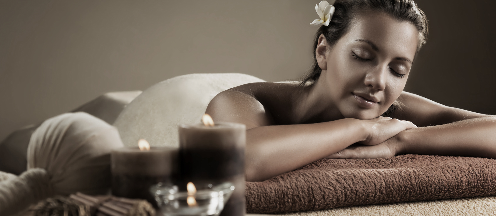 The girl relaxes in the spa salon. Beautiful setup with candles and herbal balls on the foreground.